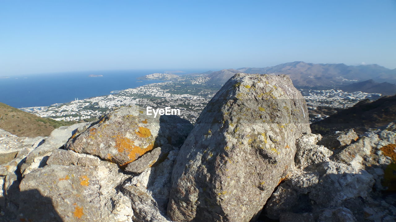 Close-up of rocks by sea against clear sky