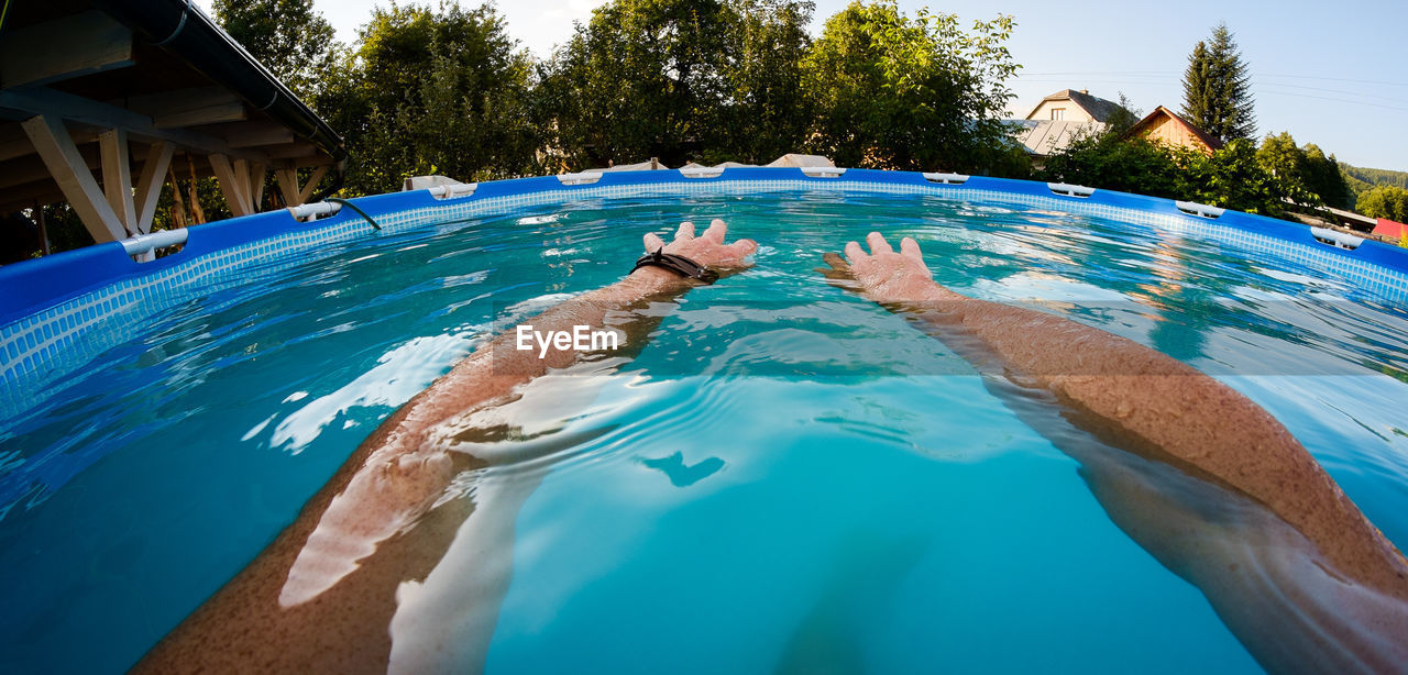 SWIMMING POOL AGAINST BLUE SKY WITH TREES