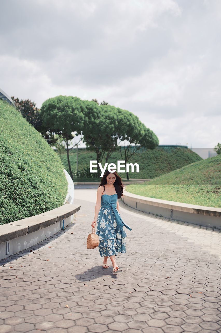 Full length of woman walking on footpath against sky