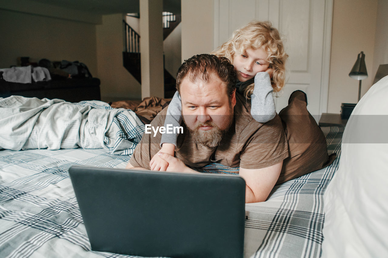 Work from home with kids children. father working on laptop in bedroom with child daughter 