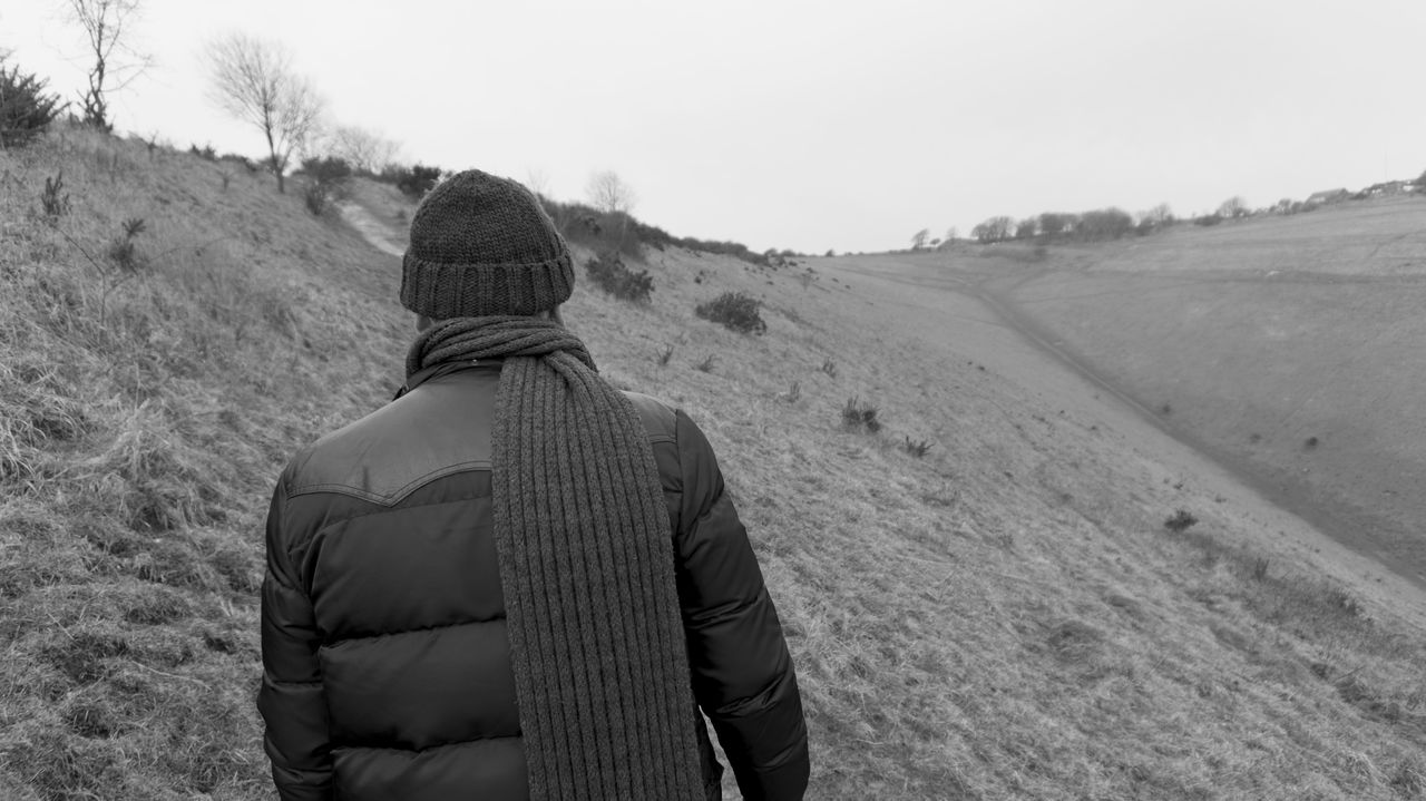 Rear view of man standing on hill against sky