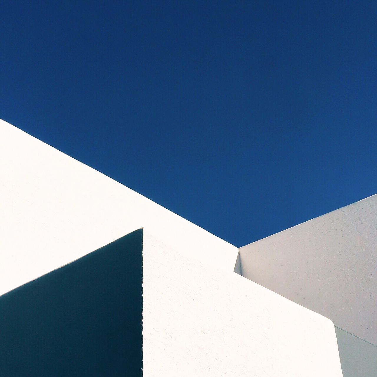 High section of white wall against clear blue sky