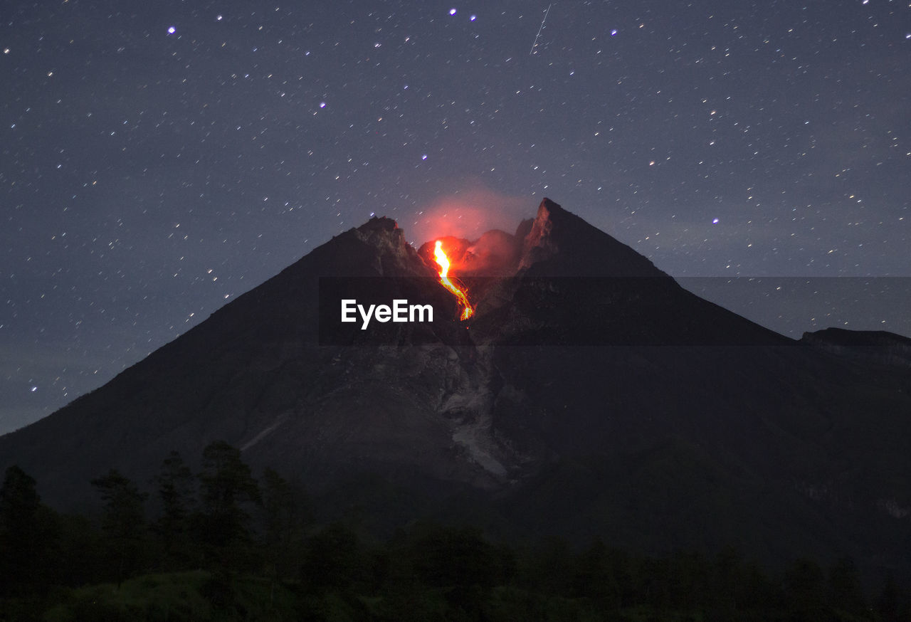 Low angle view of volcano against sky at night