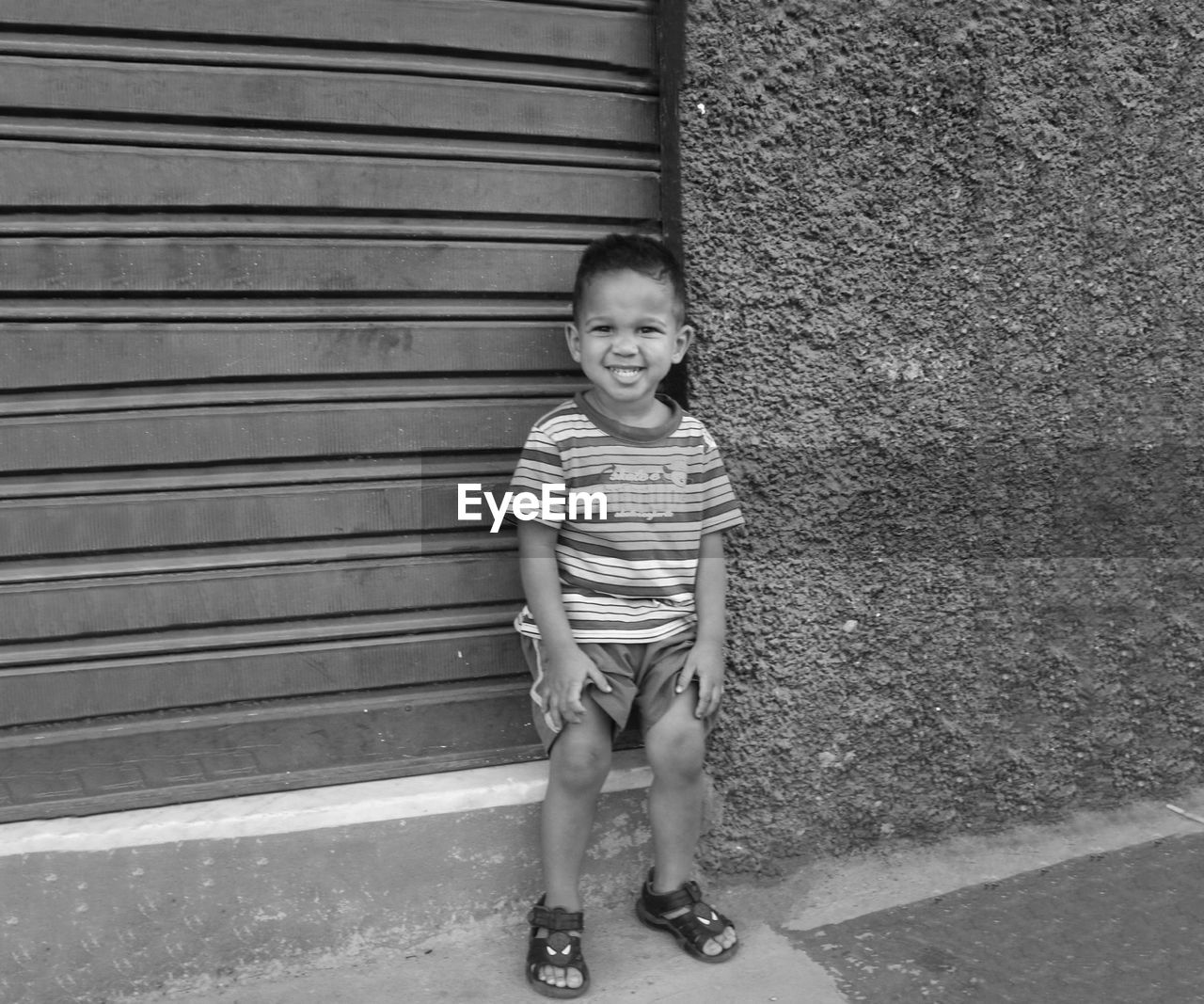 Portrait of smiling boy standing by building