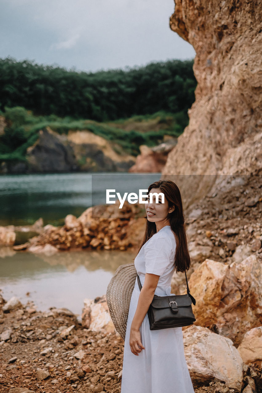 Side view portrait of woman standing by rocks