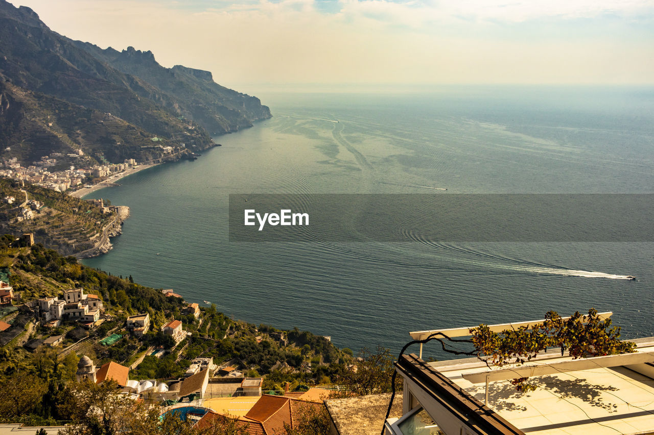 HIGH ANGLE VIEW OF BUILDINGS AND SEA AGAINST SKY