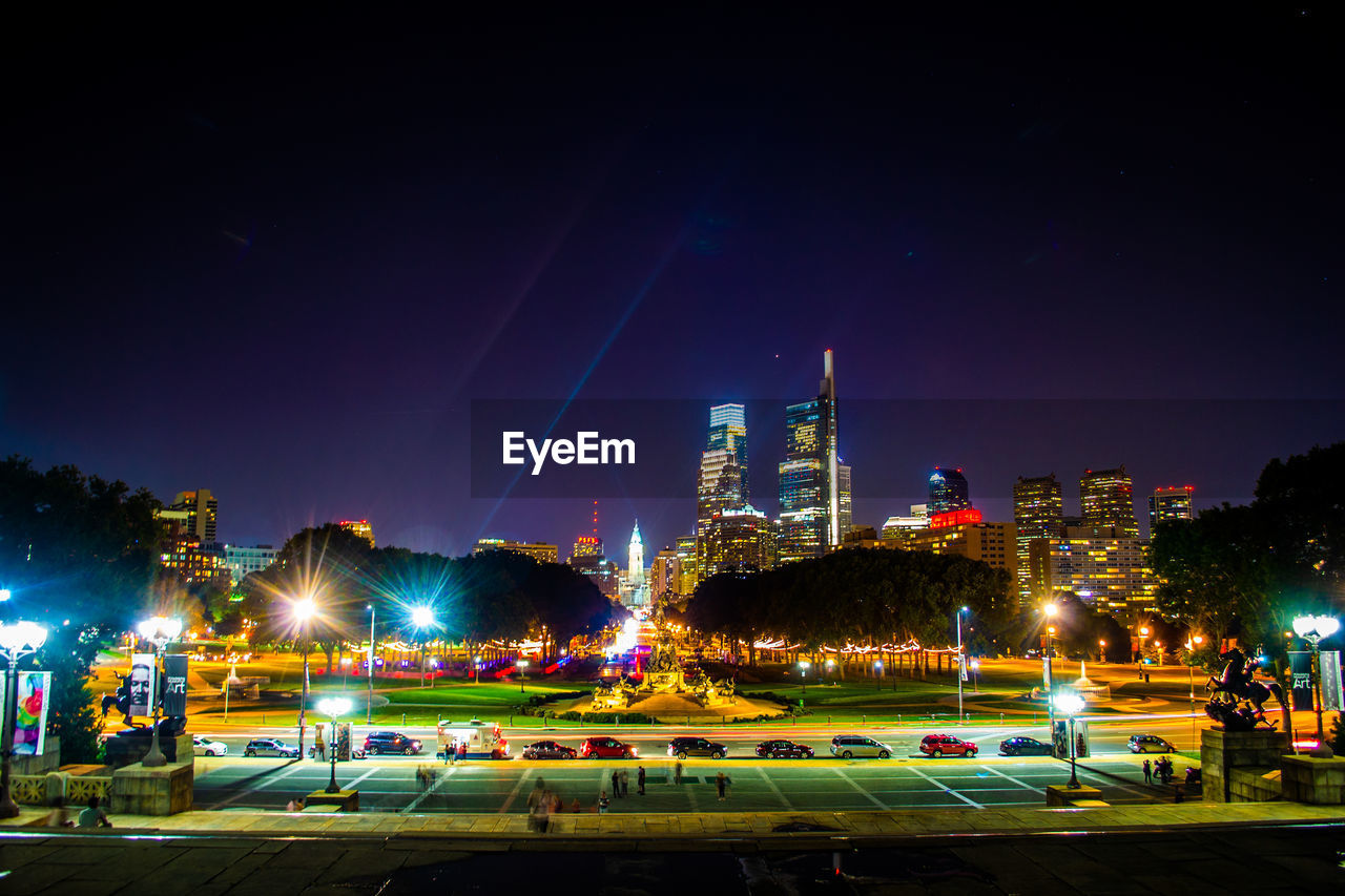 Illuminated street and buildings against sky at night