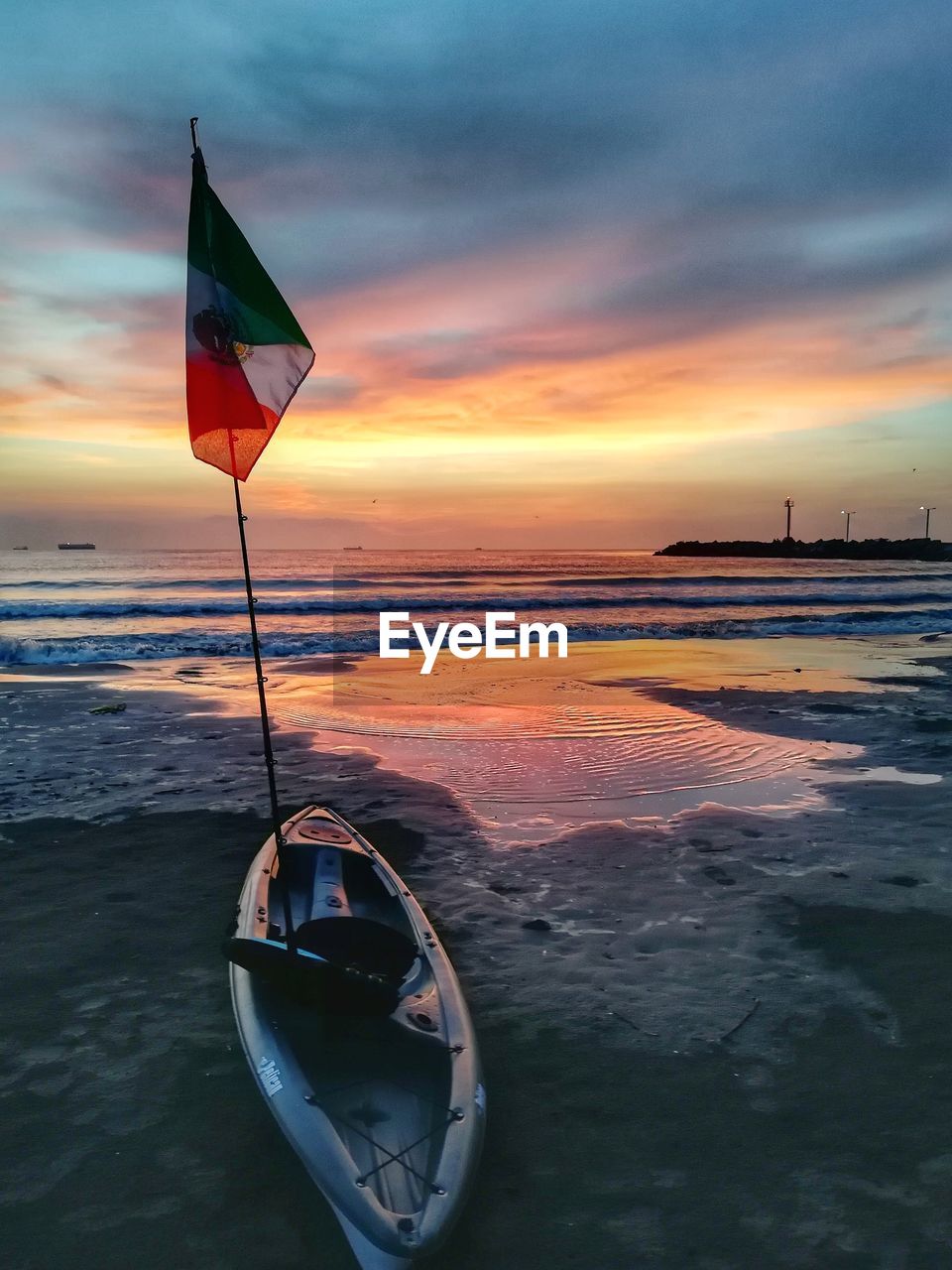 Kayak at beach against sky during sunset