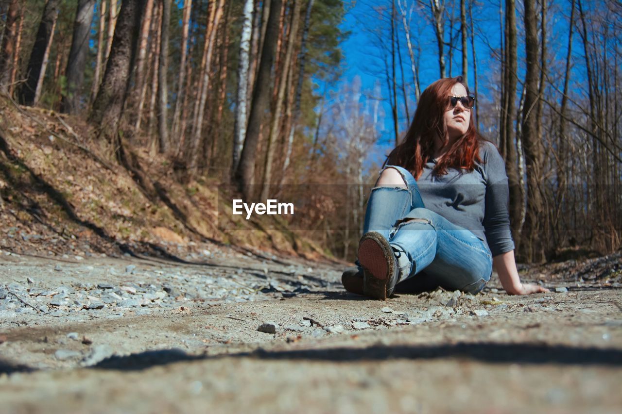 Woman sitting against trees in forest