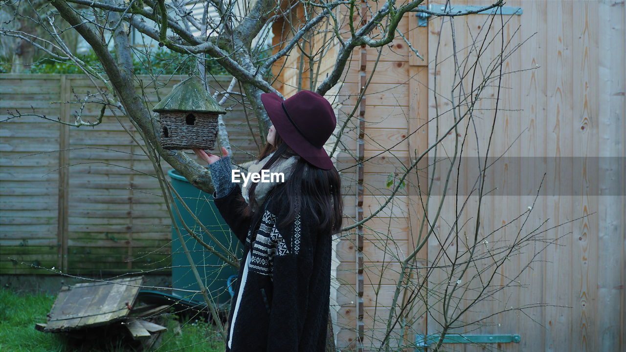 Woman looking at birdhouse on tree