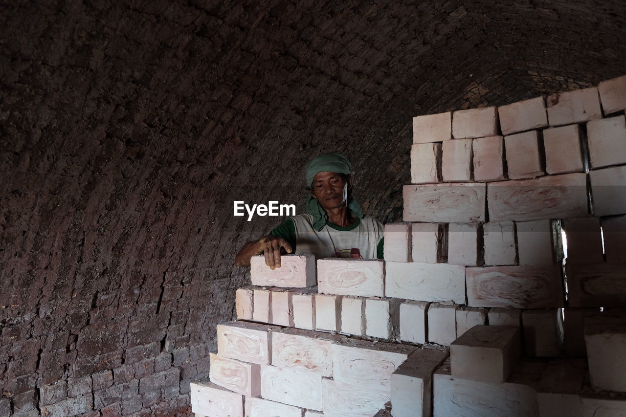 Man arranging bricks in tunnel