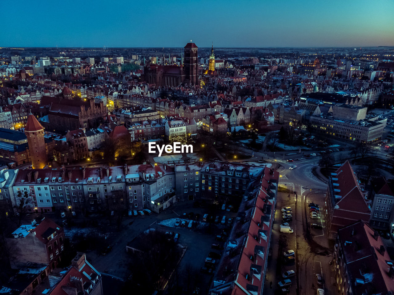 HIGH ANGLE VIEW OF ILLUMINATED STREET AMIDST BUILDINGS AT NIGHT