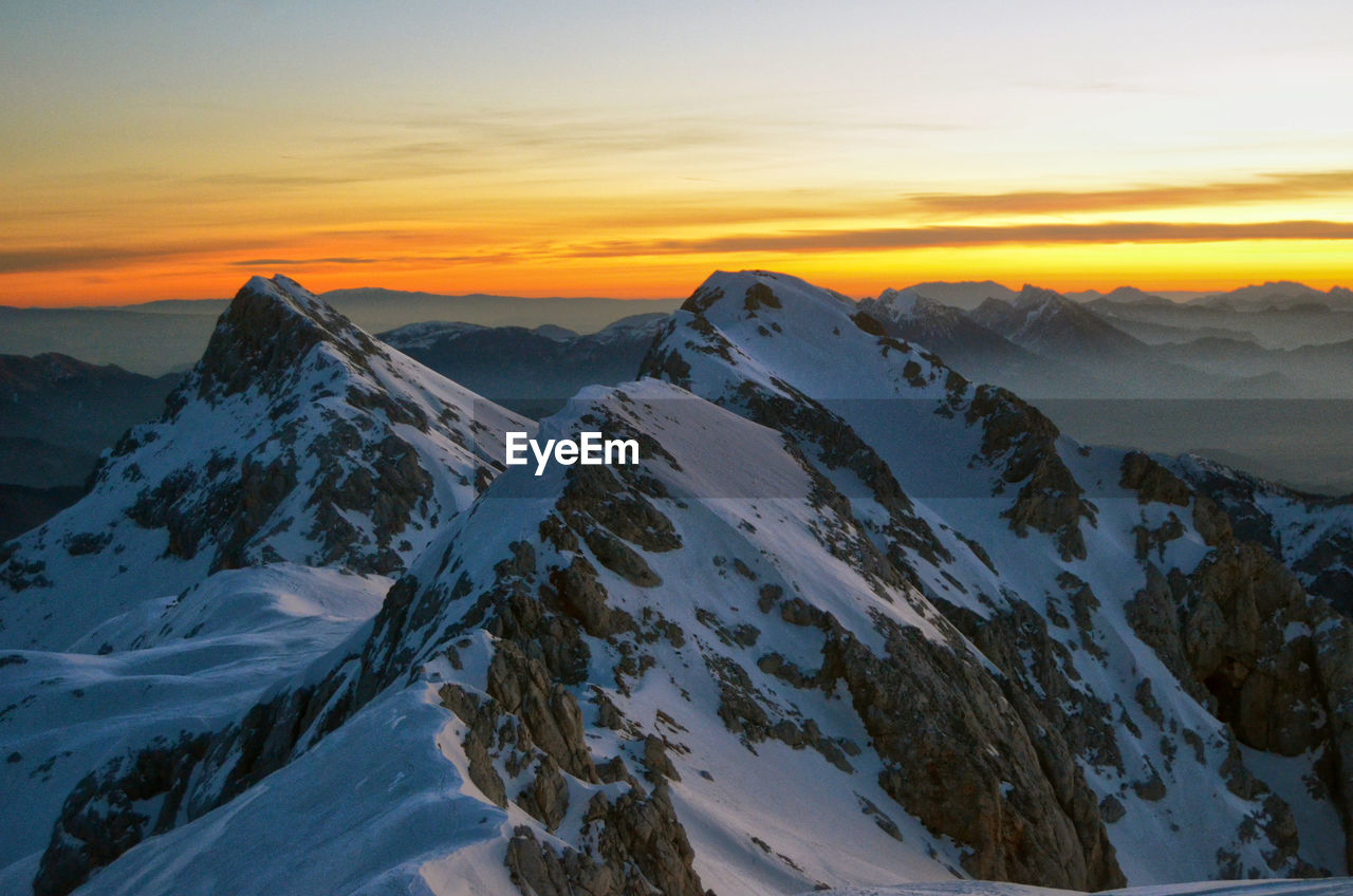 Scenic view of snowcapped mountains against sky during sunset