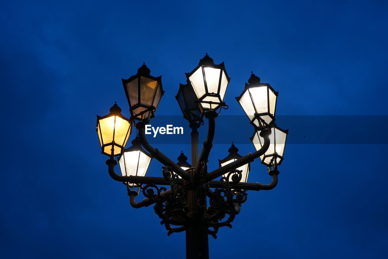 Low angle view of illuminated street light against blue sky