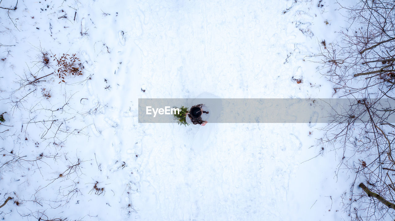 High angle view of bride wearing wedding dress while standing on snow