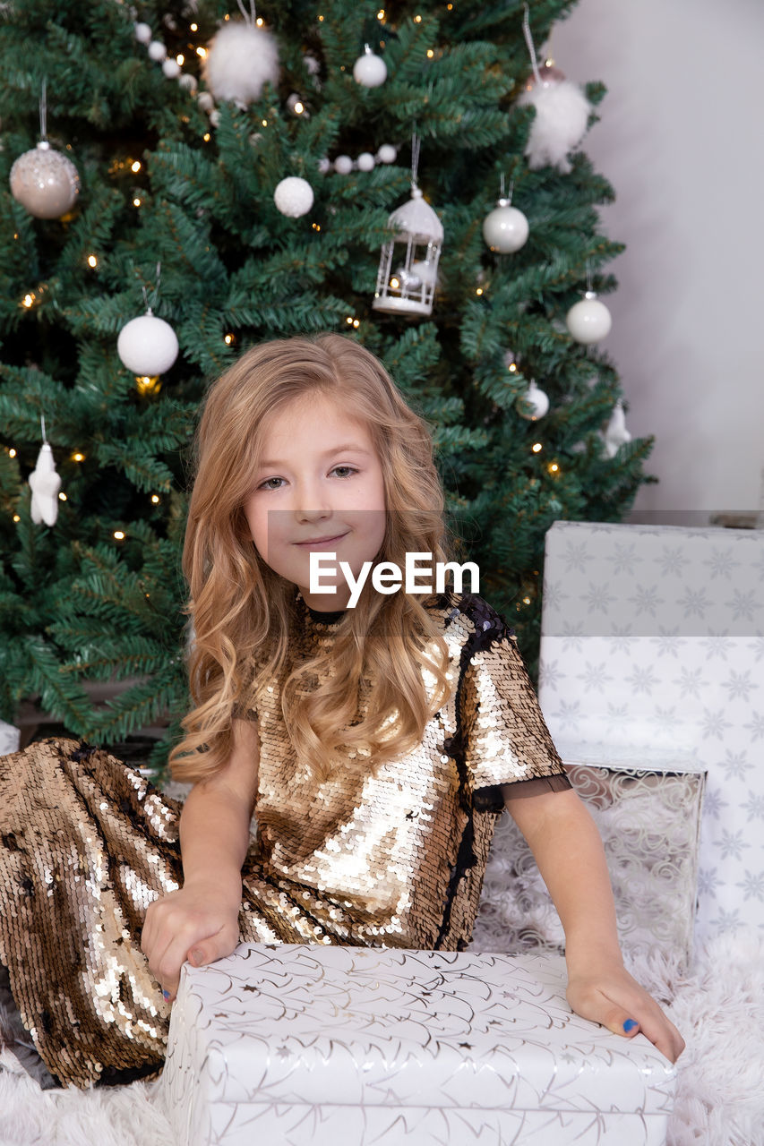 PORTRAIT OF SMILING GIRL WITH CHRISTMAS TREE