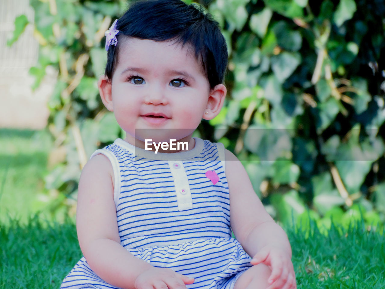 portrait of cute girl looking away while sitting on field