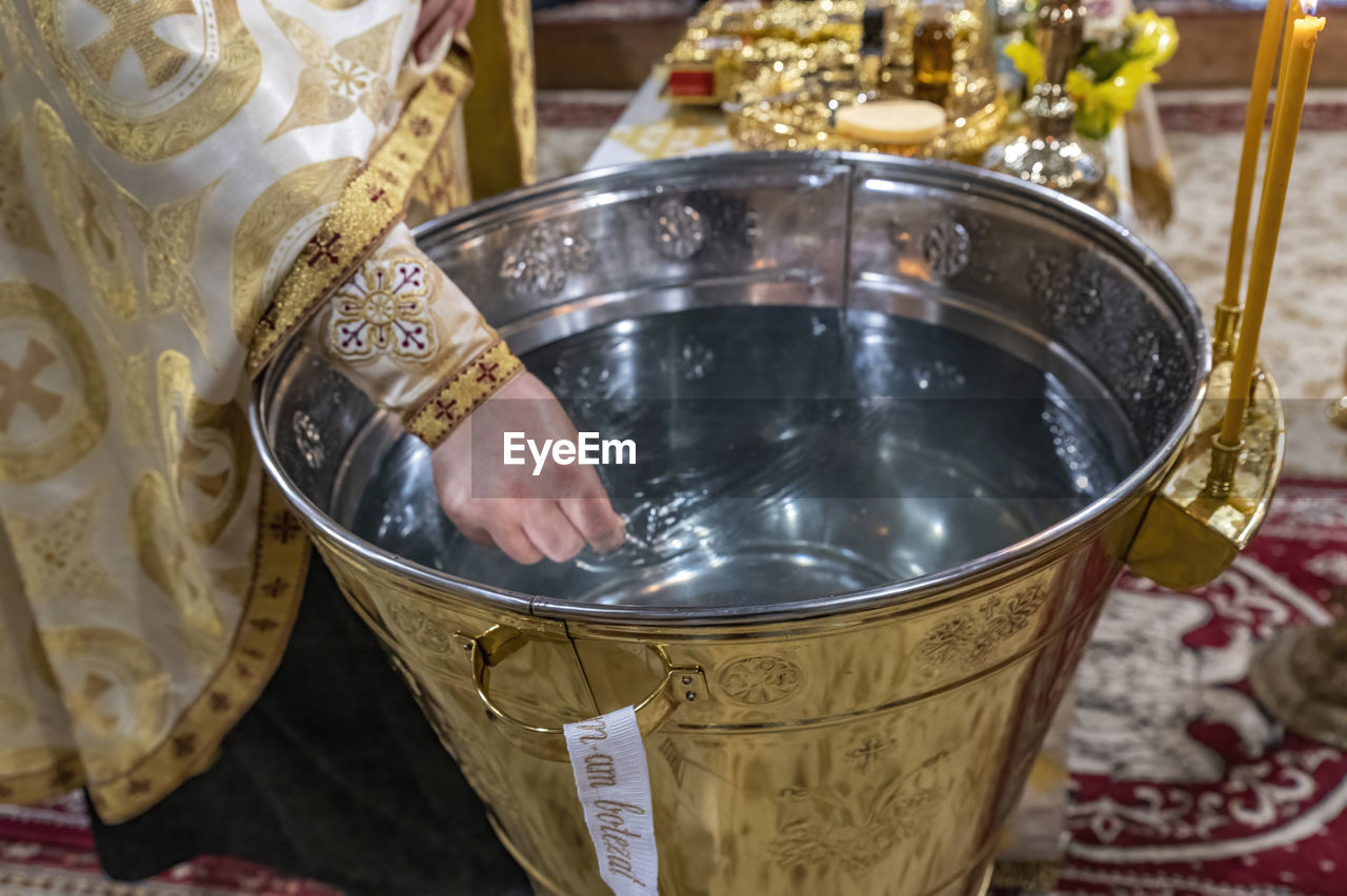 indoors, household equipment, tradition, focus on foreground, hand, food and drink, close-up, kitchen utensil, gold, one person, belief, metal, religion, silver