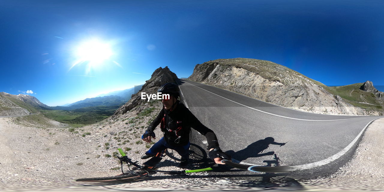 mountain, sky, nature, adventure, sports, extreme sports, sunlight, environment, activity, leisure activity, scenics - nature, landscape, mountain range, travel, adult, beauty in nature, full length, mountaineering, travel destinations, one person, day, land, sunny, outdoors, blue, transportation, motion, holiday, vacation, men, clear sky, hiking, trip, sports equipment, non-urban scene, lifestyles, lens flare, sun, snow, mountain climbing, exploration, cold temperature, challenge, recreation, tranquility, mountain peak