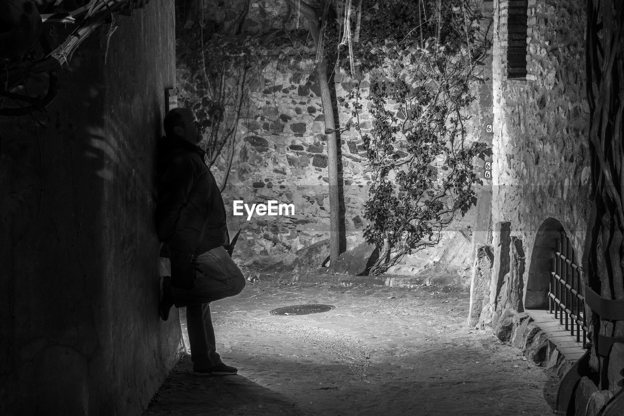 Side view of man standing by wall