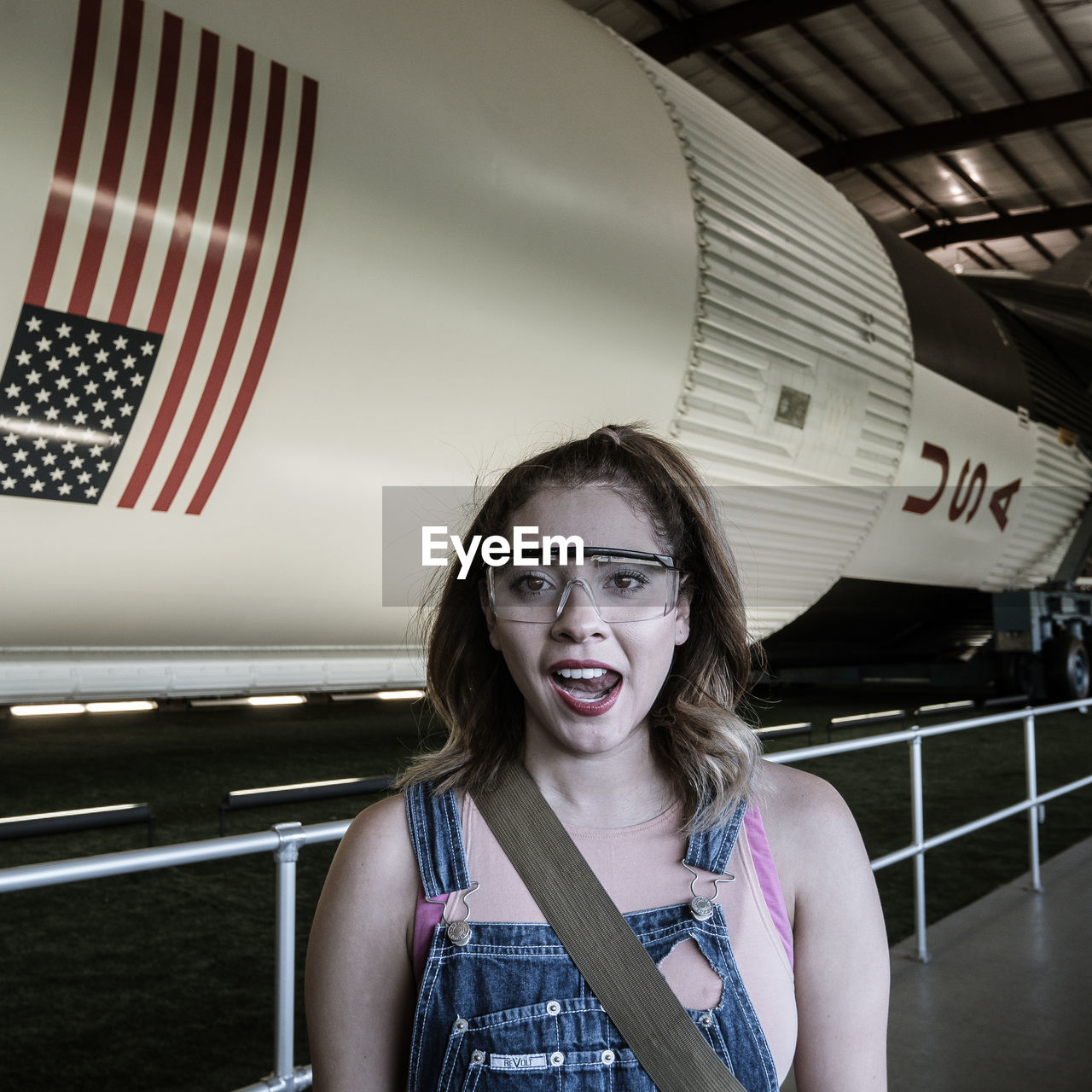 Portrait of young woman standing against rocket