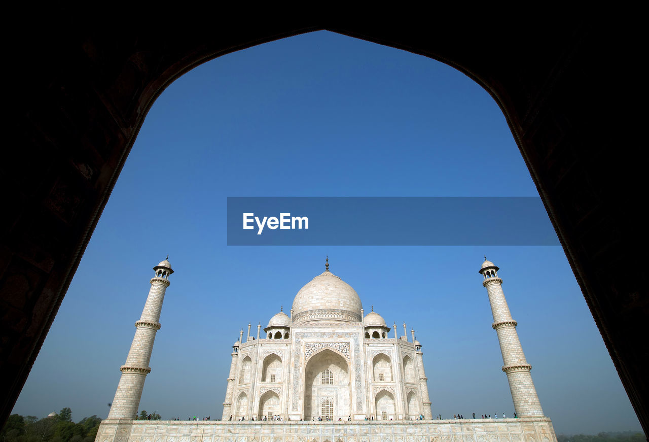 Low angle view of taj mahal seen through arch against clear sky