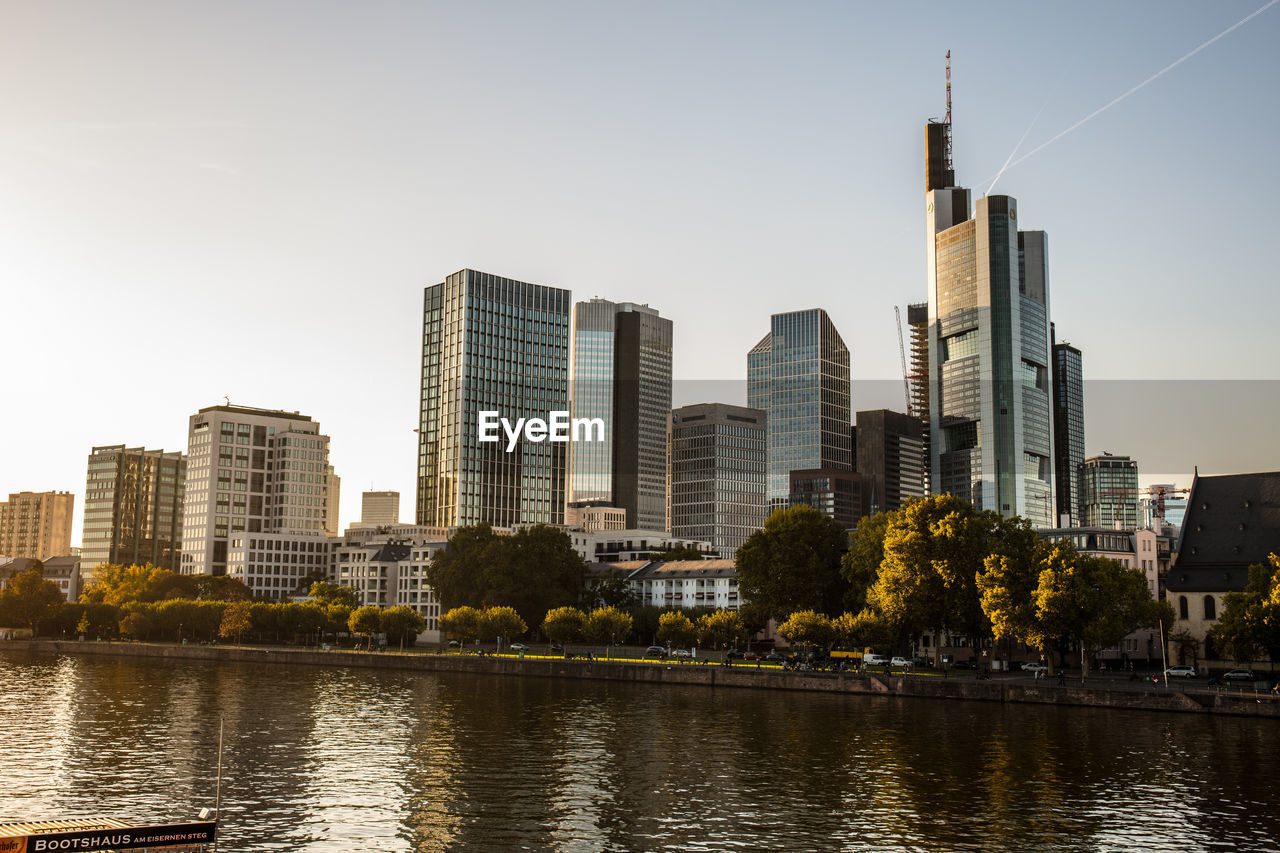 Buildings by river against sky in city
