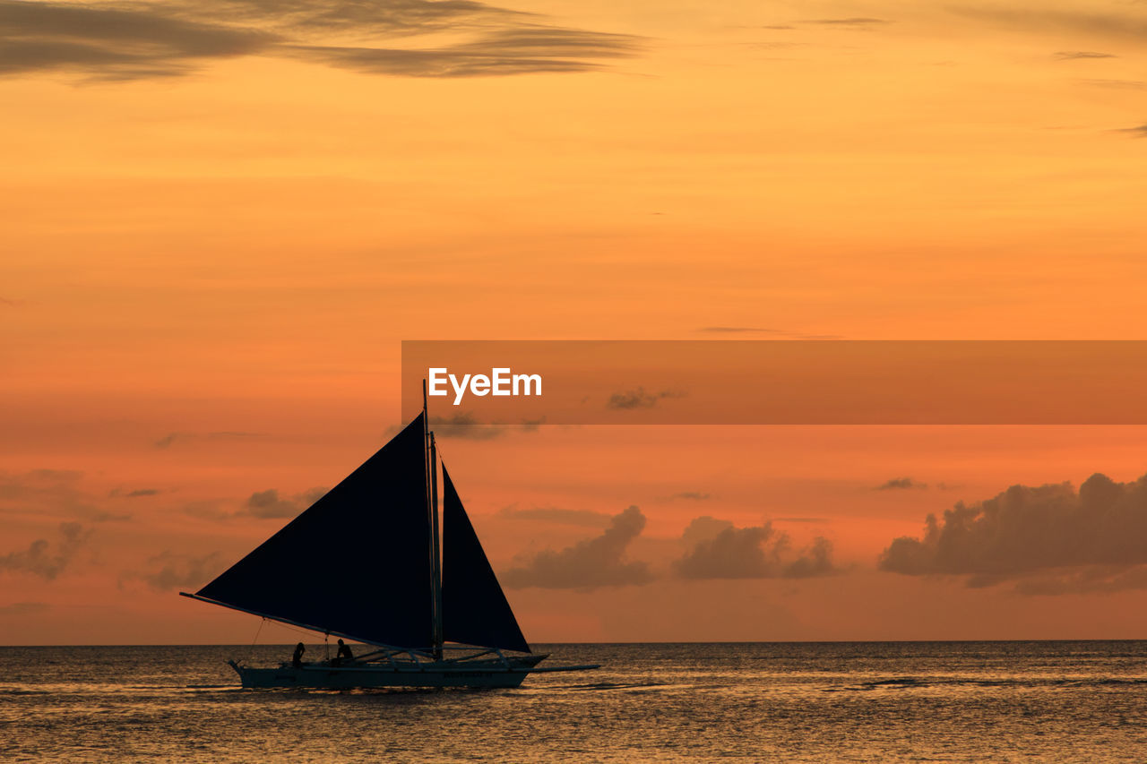 Sailboat on sea against sky during sunset