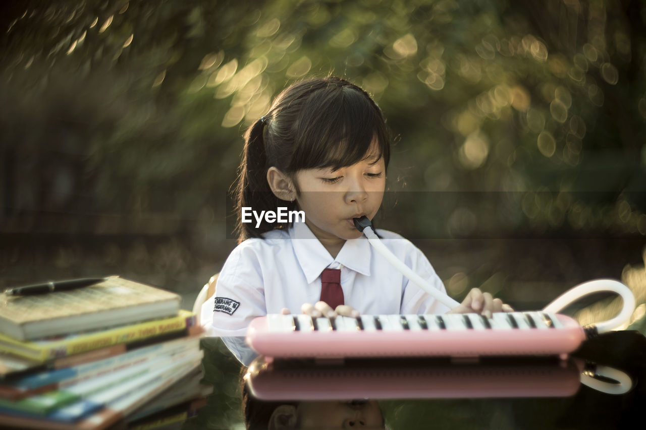 Cute girl playing piano while sitting at desk