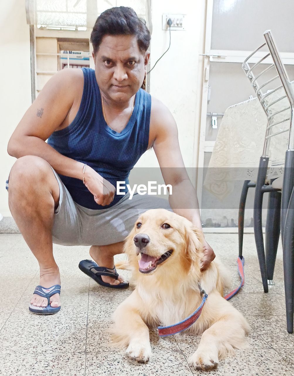 PORTRAIT OF YOUNG MAN WITH DOG SITTING ON FLOOR