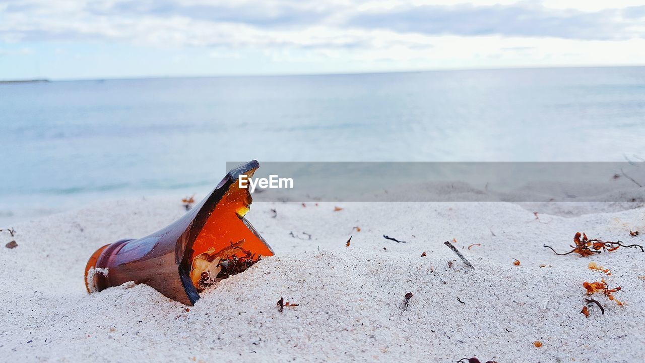 Broken bottle on white sand beach