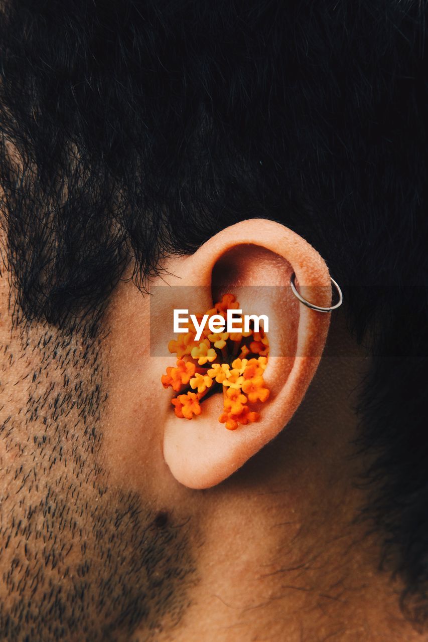 Close-up of man with flowers in ear