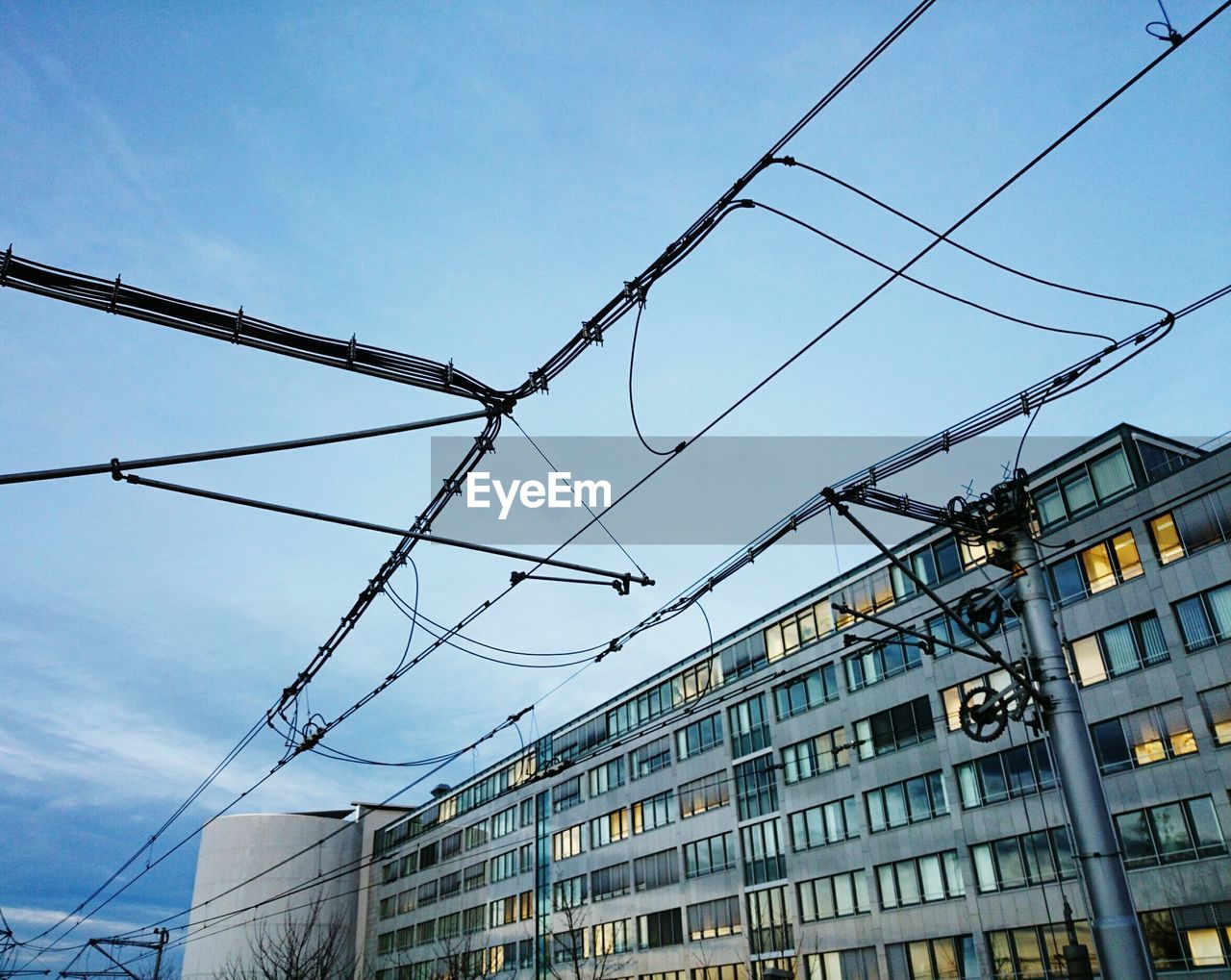 Low angle view of electricity pylons by buildings in city