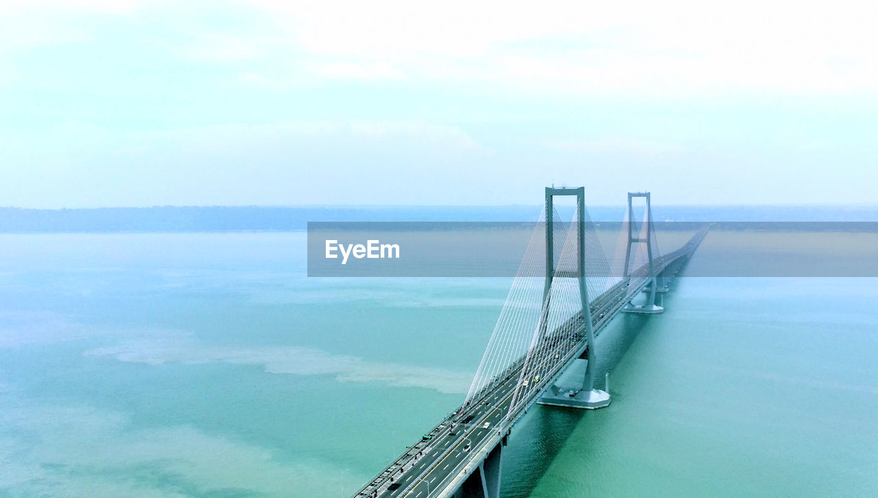 water, sea, transportation, sky, nature, scenics - nature, cloud, beauty in nature, no people, day, travel, tranquility, bridge, tranquil scene, architecture, coast, horizon, nautical vessel, horizon over water, outdoors, high angle view, built structure, mode of transportation, bay, vehicle, travel destinations, ocean, copy space, aerial view, idyllic, environment, land, blue, railing, tourism, suspension bridge