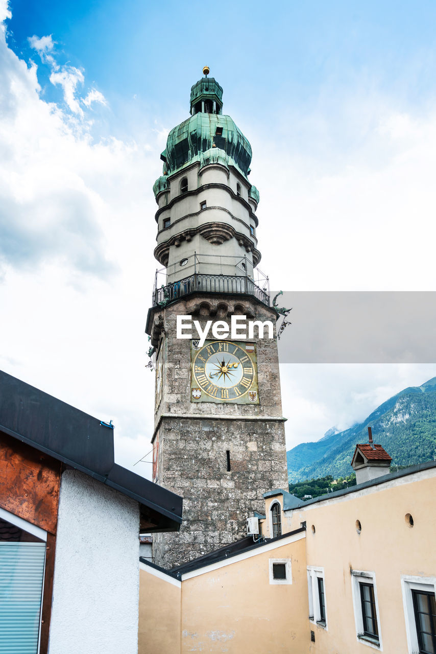 Low angle view of clock tower in city against cloudy sky