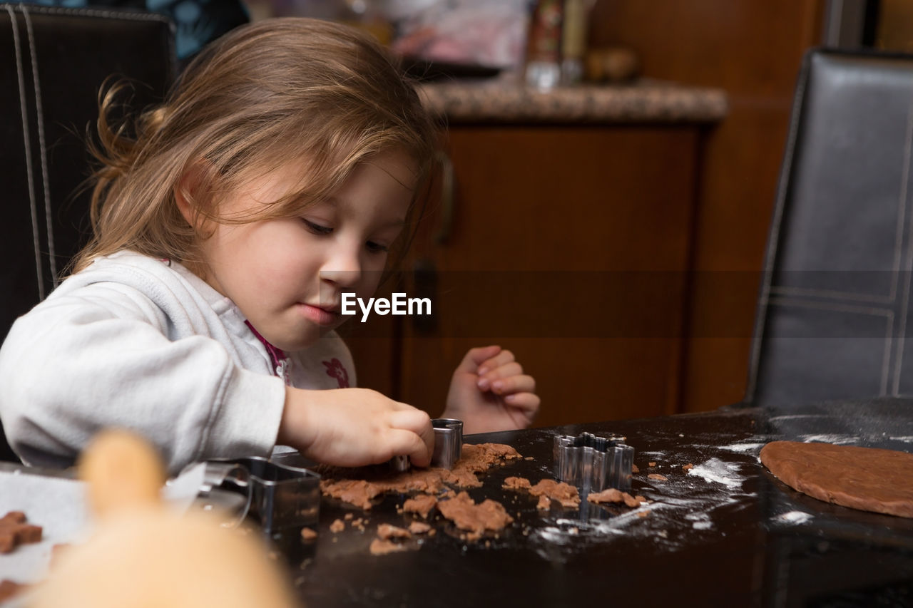 Girl preparing cookie on kitchen island at home