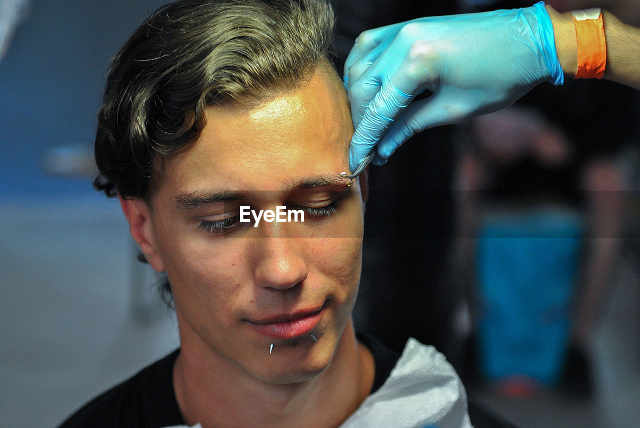 Cropped hand piercing man eyebrow