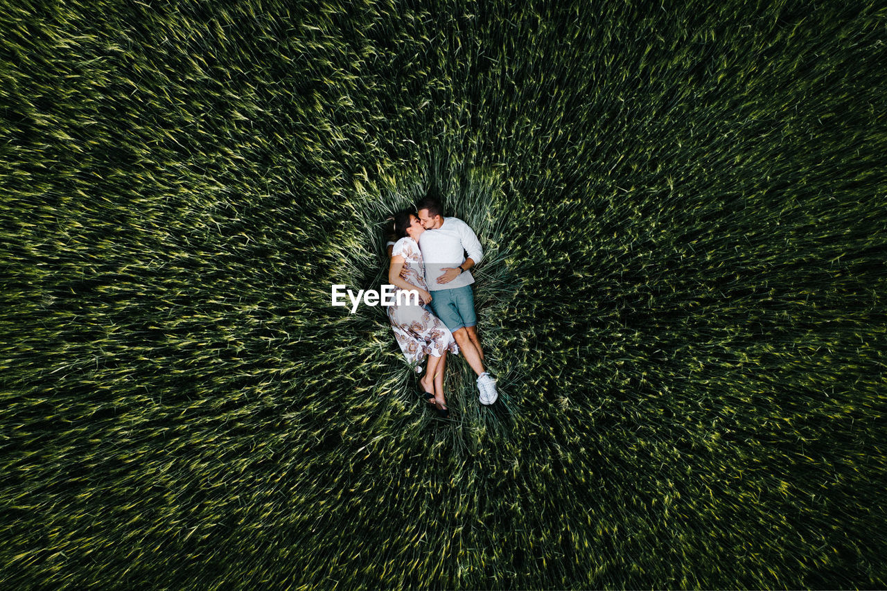 HIGH ANGLE VIEW OF MAN AND WOMAN STANDING AT THE EDGE OF PALM TREE