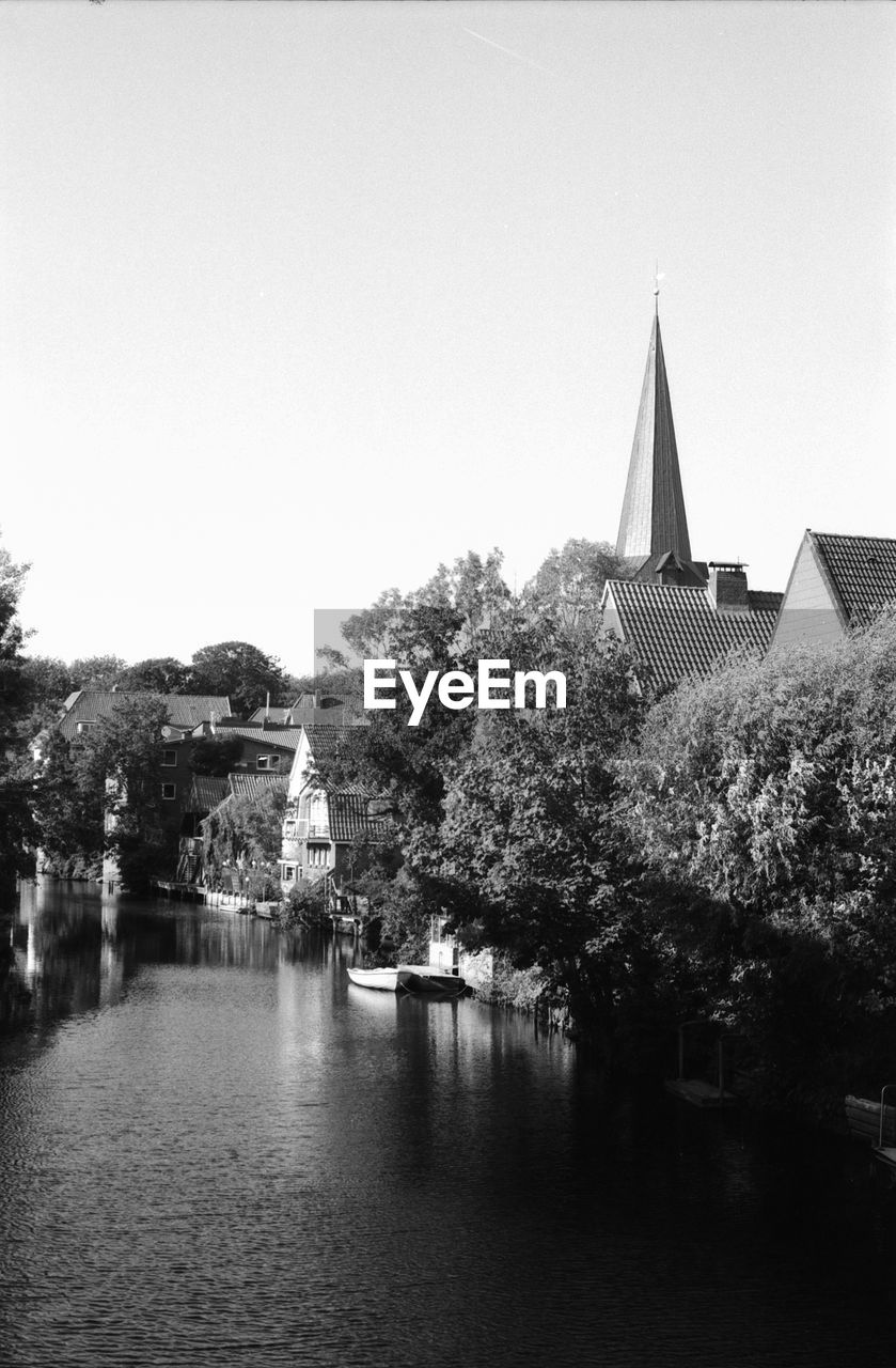 BUILDINGS BY TREES AGAINST CLEAR SKY