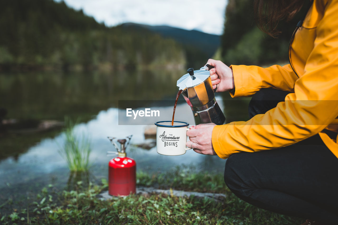 Man holding coffee by lake
