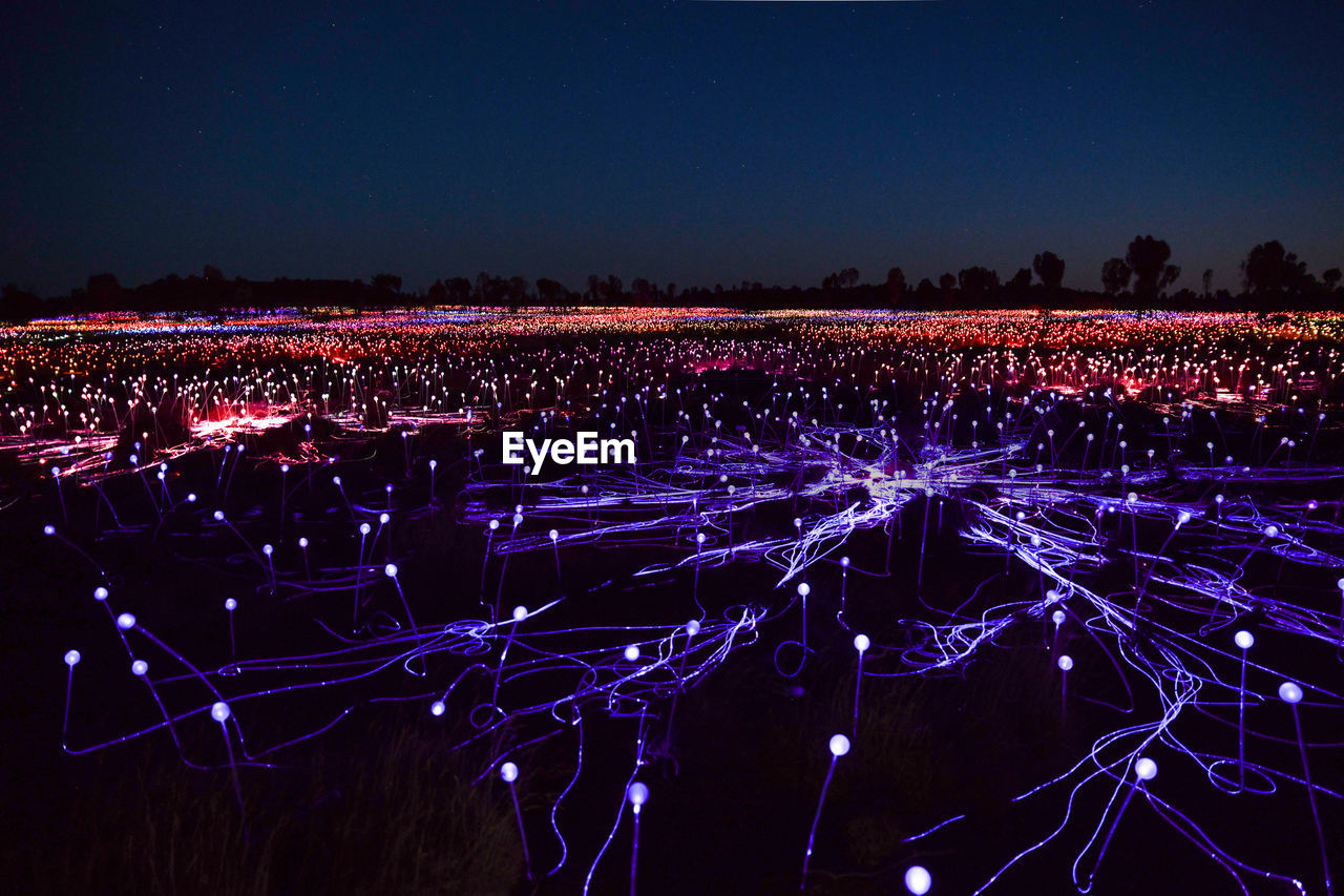 High angle view of illuminated field against clear sky at night