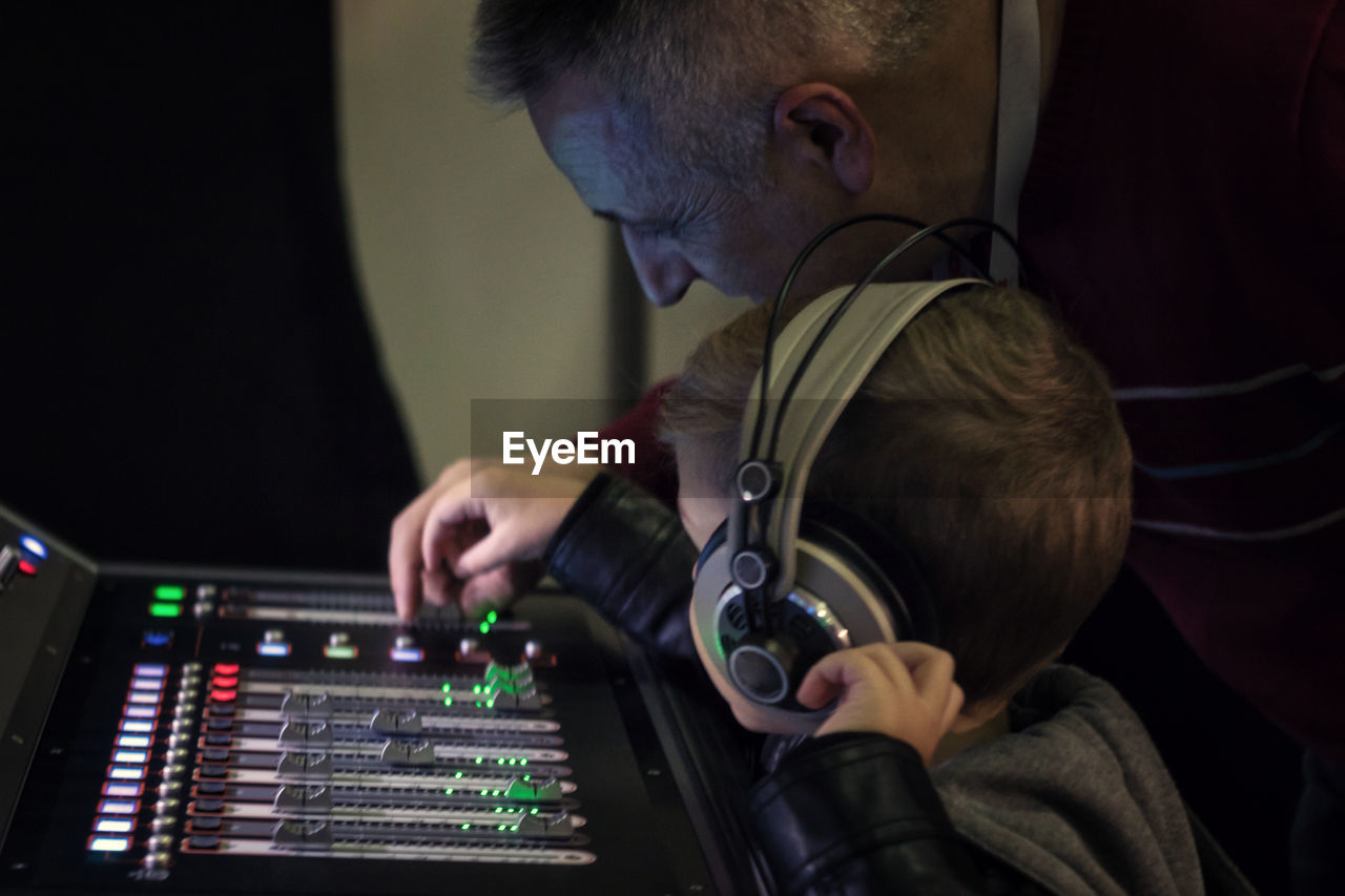 Music teacher helping boy to learn sound mixing in recording studio