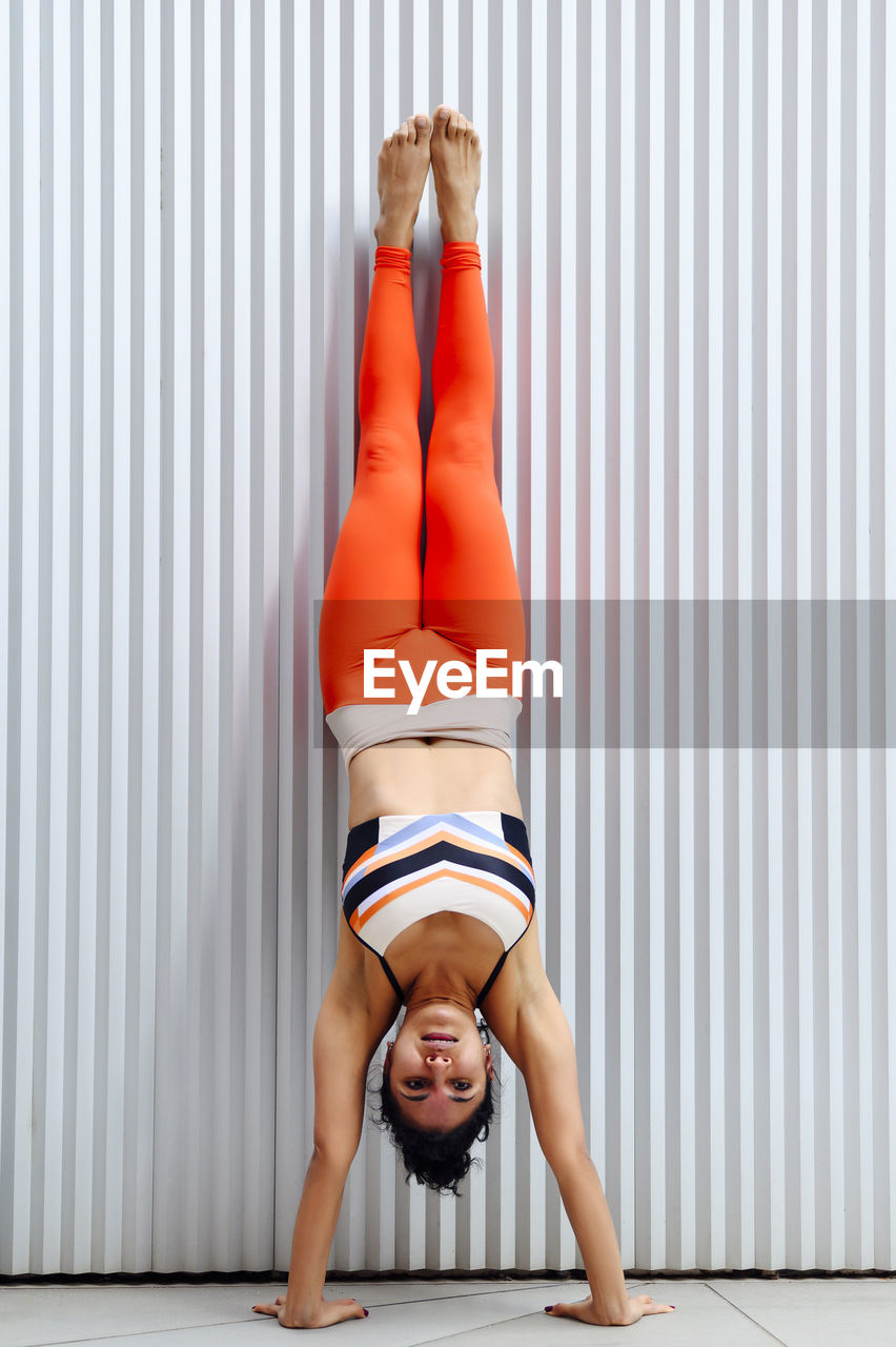 Mid adult female sportsperson doing handstand against wall