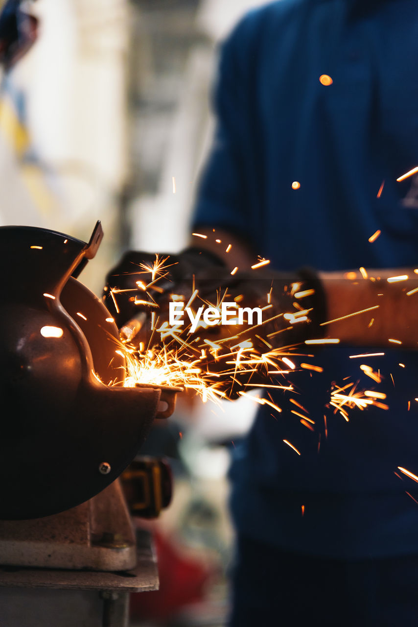 Midsection of worker working on metal at workshop