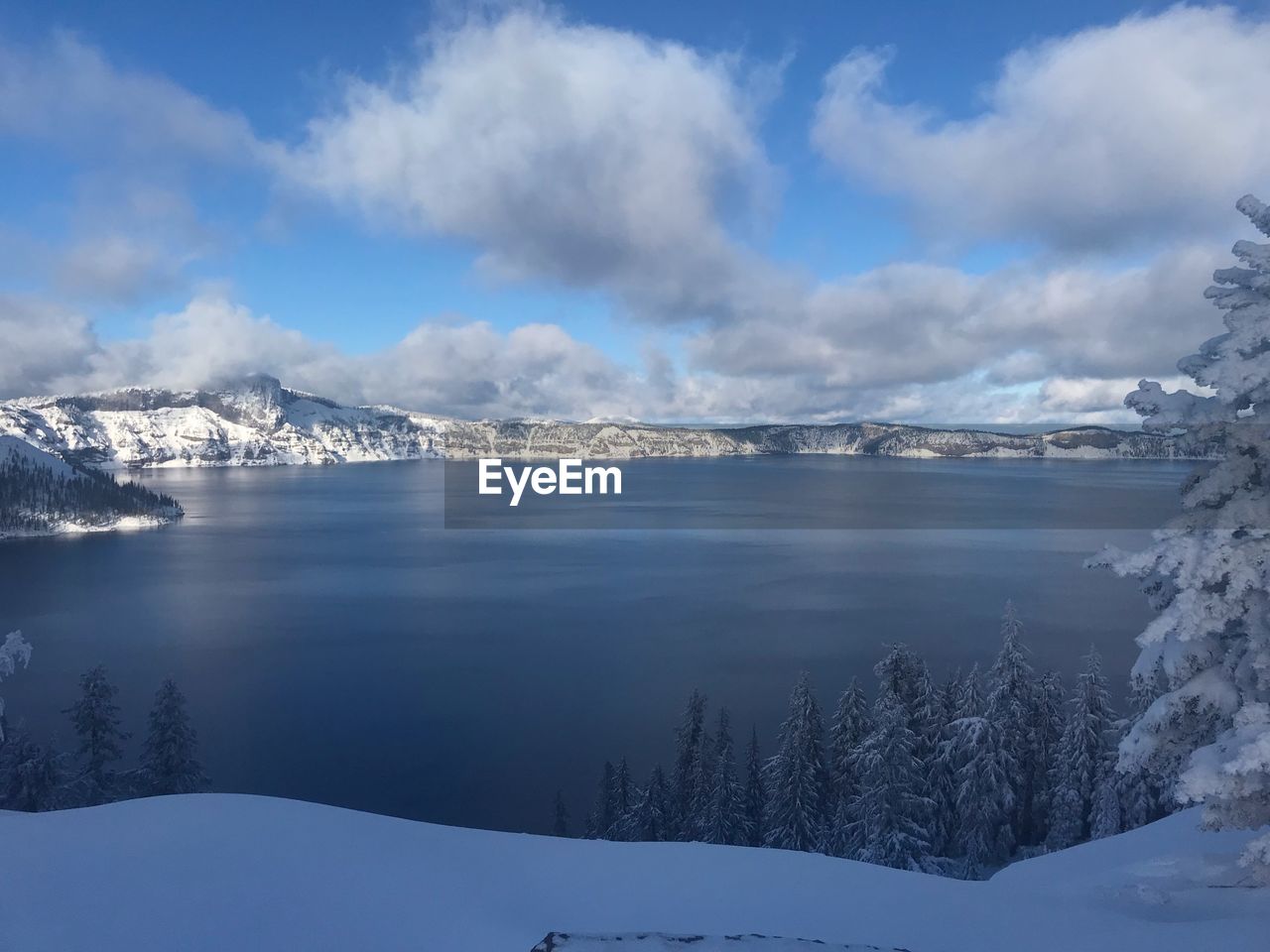 Scenic view of lake by snowcapped mountains against sky