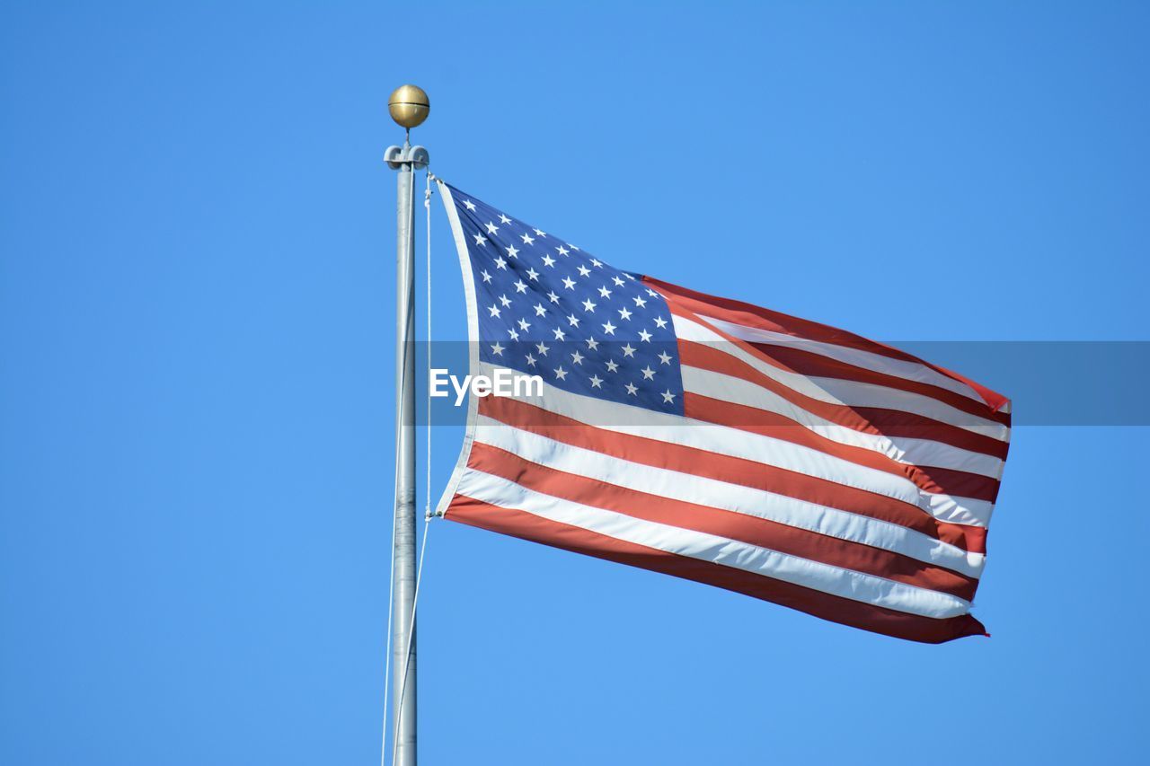 Low angle view of american flag against clear blue sky