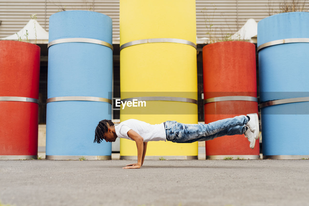 Young man practicing handstand in front of concrete pipes