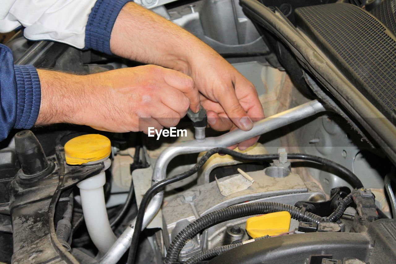 Cropped hands repairing car engine