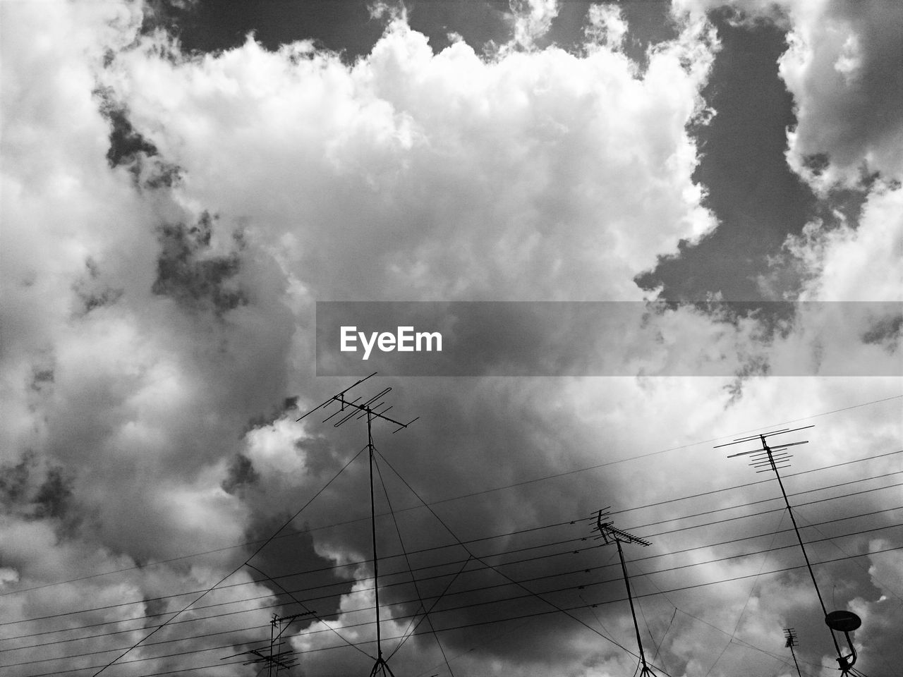 LOW ANGLE VIEW OF POWER LINES AGAINST CLOUDY SKY