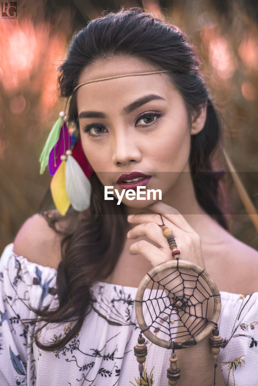 Close-up portrait of young woman with dreamcatcher